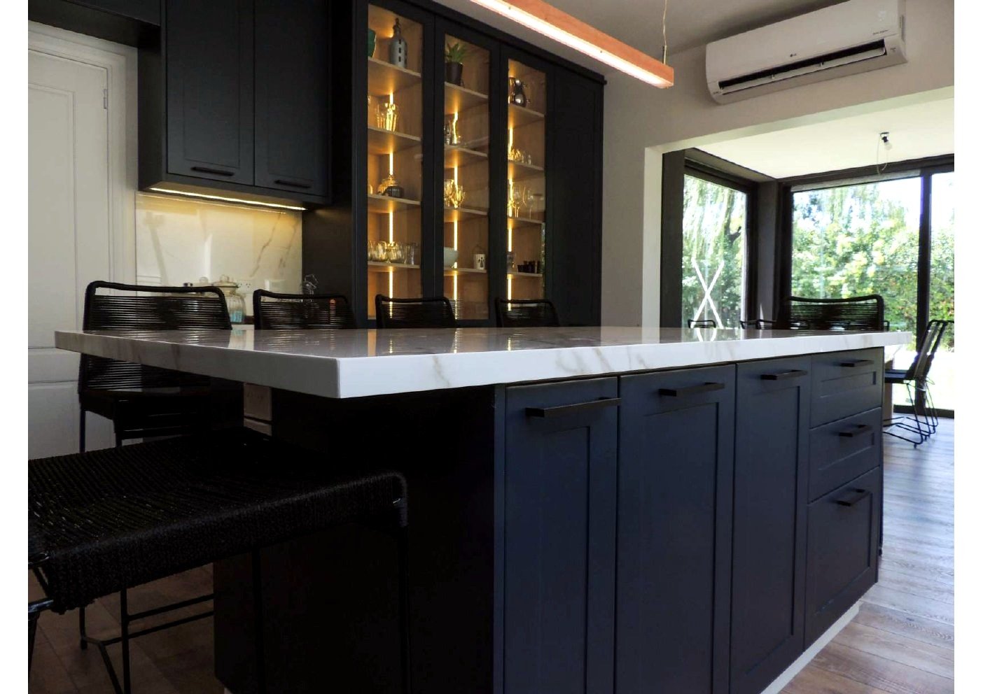 Detalle isla central cocina navy con sillas de diseño