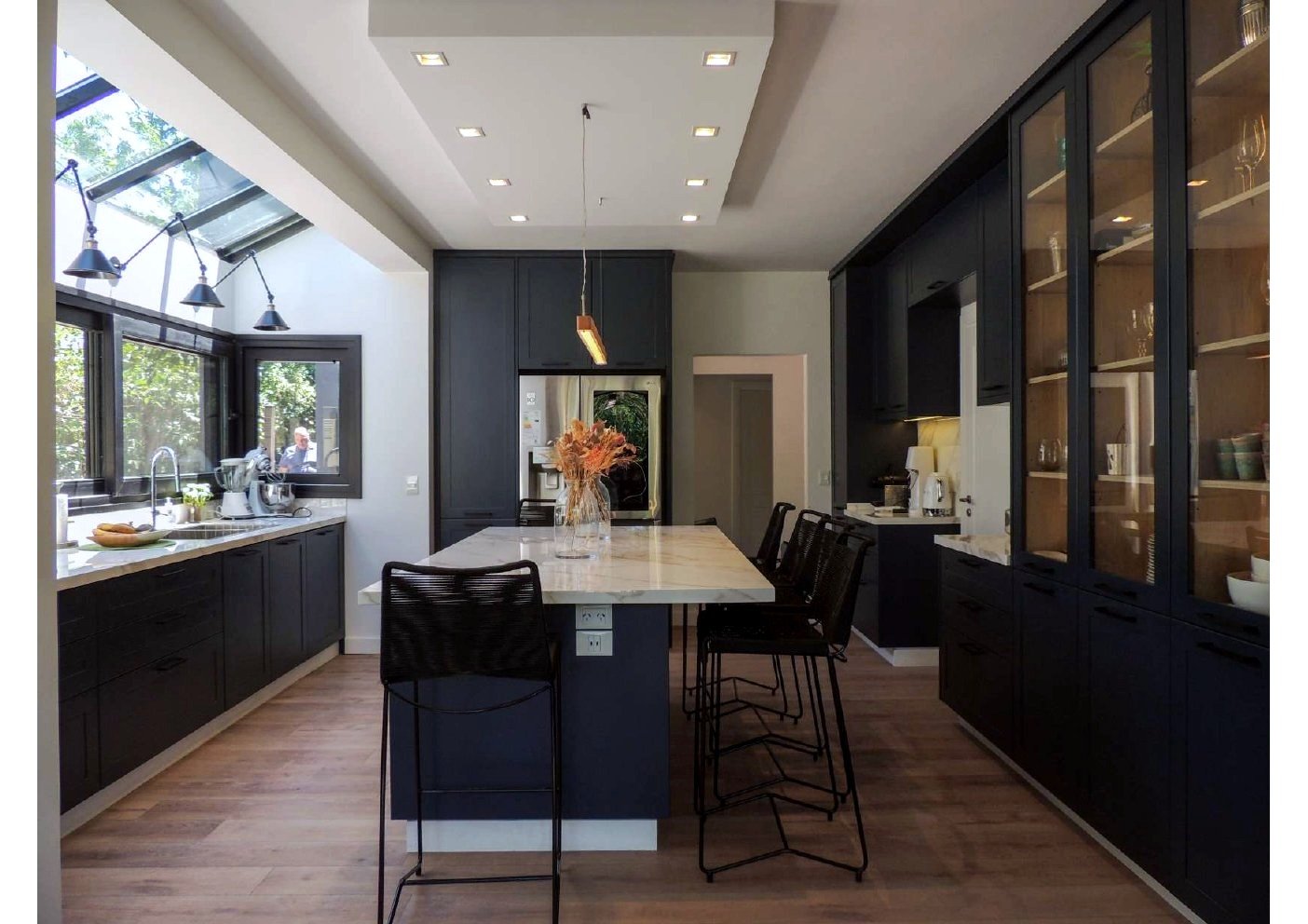 Cocina navy matte con isla de mármol calacatta y vitrinas iluminadas